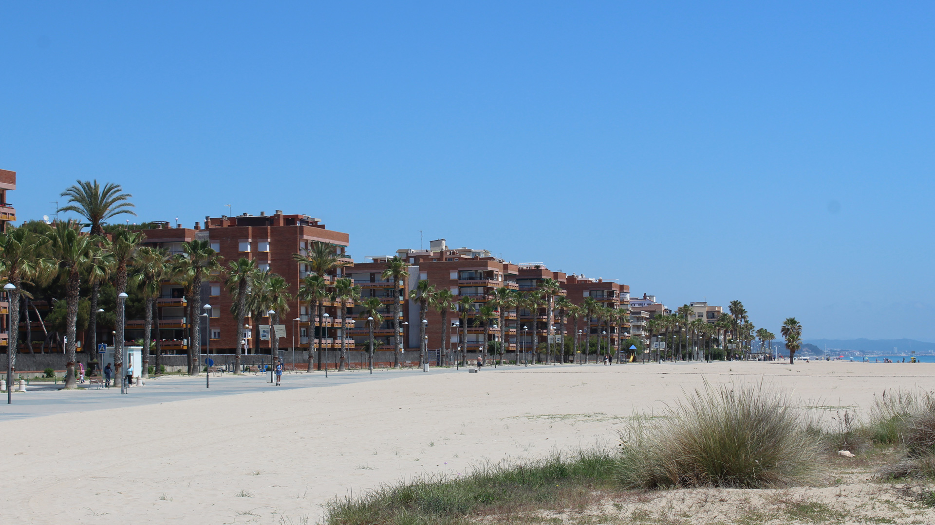 Vista de la platja i el passeig marítim de Torredembarra en un dia assolellat.